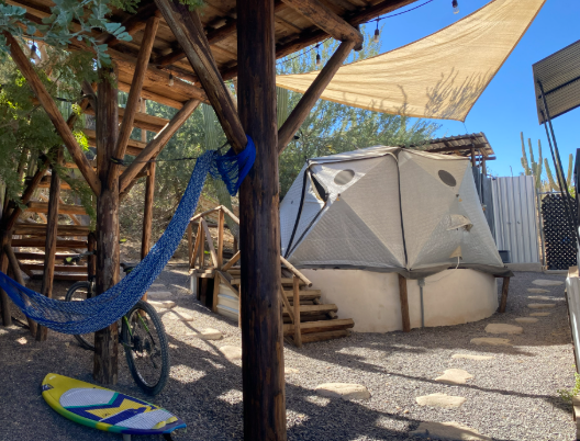 Glamping Sagitario — dome on a wooden deck with a blue hammock, surrounded by cactus under a clear sky