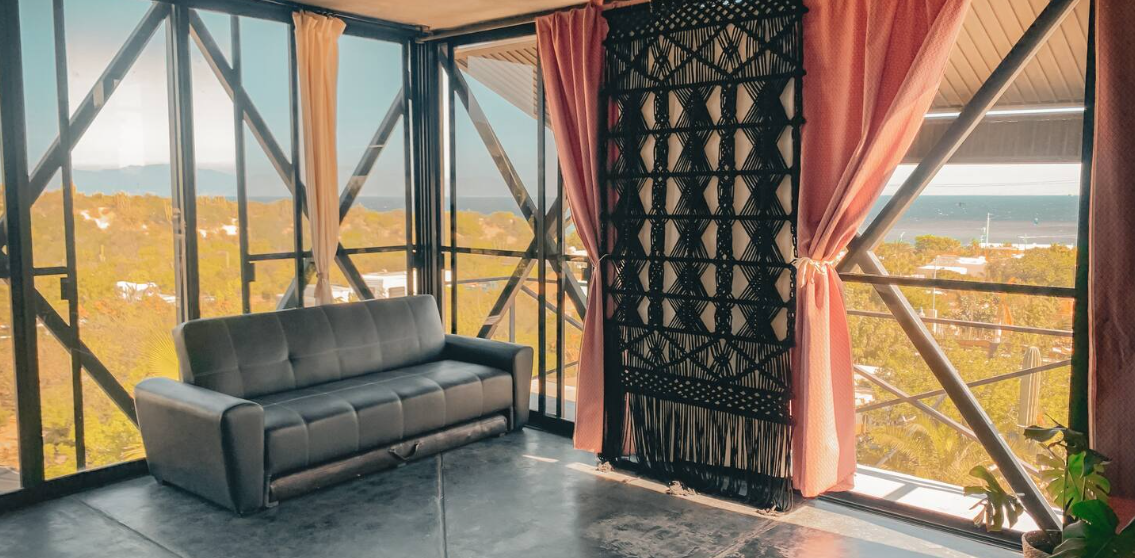 Yoga Suite — floor-to-ceiling windows with sea view and a woven macramé tapestry