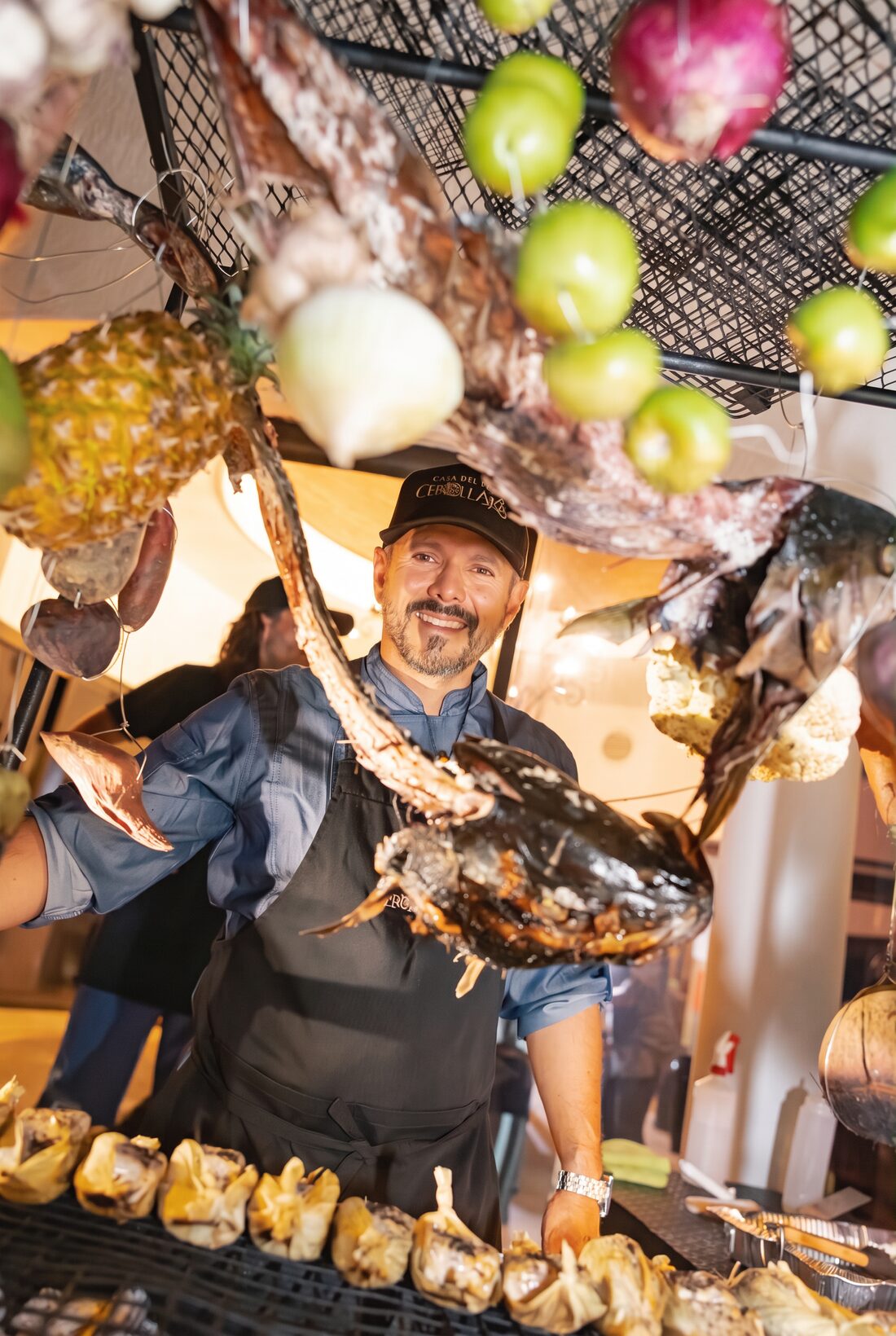 Raymond behind his cooking station, with smoked fish and produce hanging above
