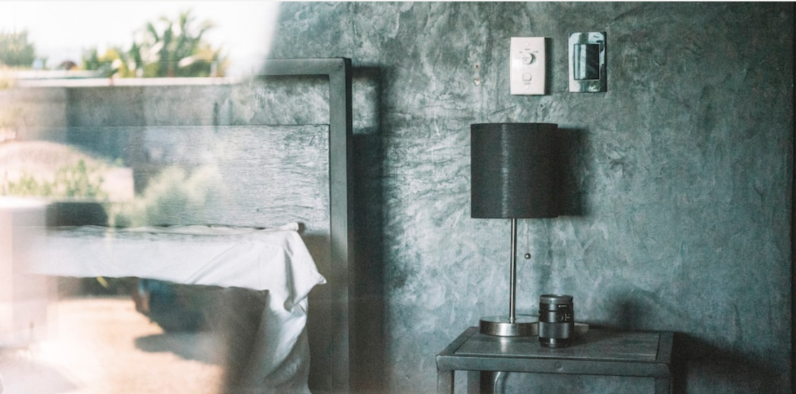 Master Suite — queen bed with white linens against a textured concrete wall