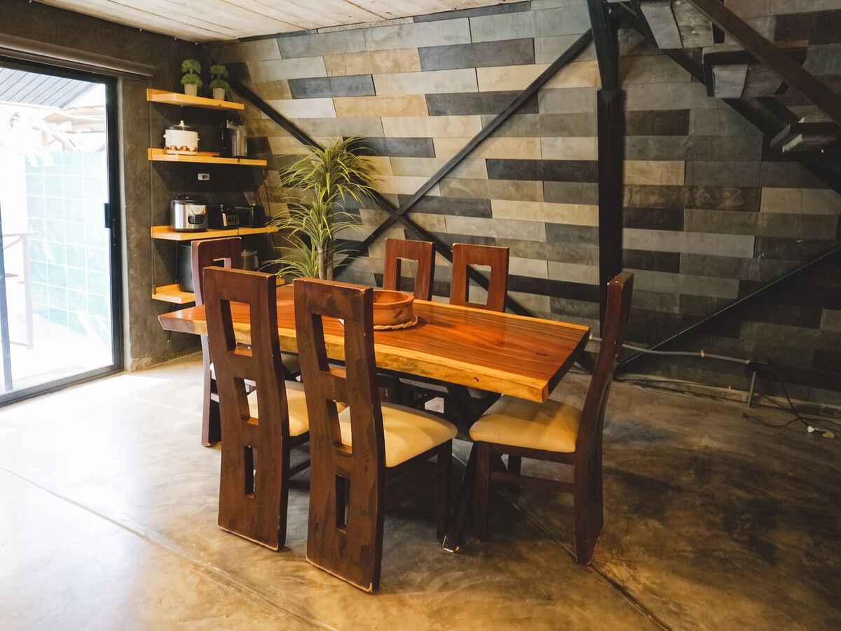 The shared dining room — a solid wood table for six under the mezzanine