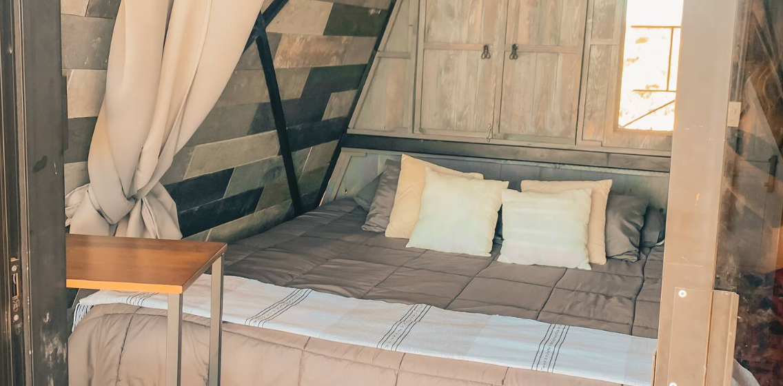 Alba Suite — bed under a sloped wooden wall with a woven throw and cushions